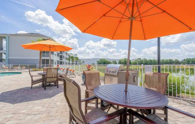 a patio with a table and chairs and orange umbrellas