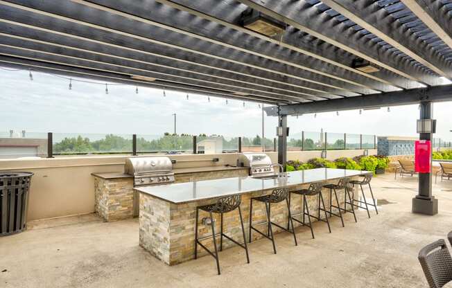 an outdoor patio with a barbecue grill and a long table with stools