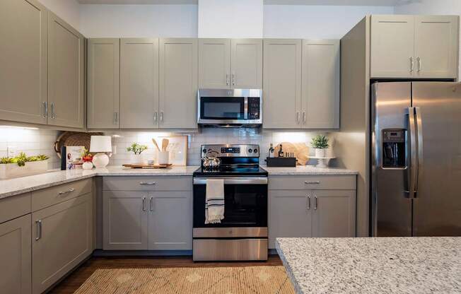 A kitchen with a refrigerator, oven, and microwave.
