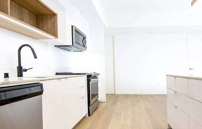 A modern kitchen with wooden floors and white cabinets.at The Dillon, Los Angeles California