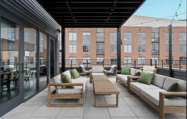 a rooftop patio with couches and tables and a brick building