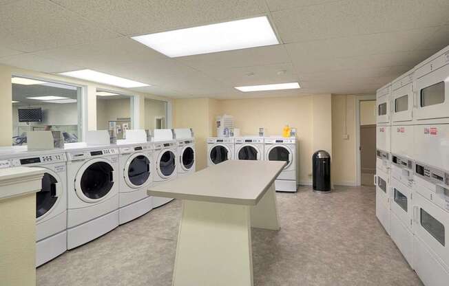 A laundry room with washing machines and a folding table.