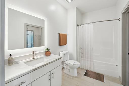A white bathroom with a toilet, sink, and shower at The Waterford At Rocketts Landing Apartments, PRG Real Estate, Richmond, Virginia