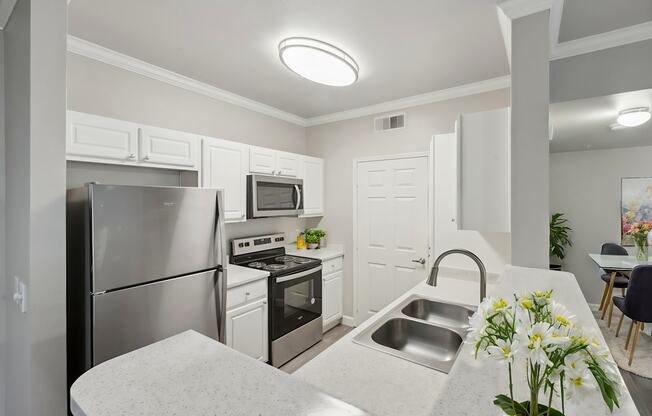 A kitchen with a stainless steel refrigerator, microwave, oven, and sink.