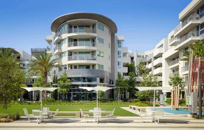A white building with a curved design and a pool in front. at Elements Apartments*, Irvine