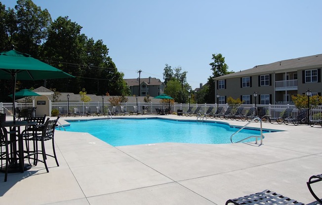 A large swimming pool surrounded by a fence and chairs.