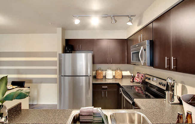 A modern kitchen with a stainless steel refrigerator and dark brown cabinets. at Mill Creek Meadows Apartments, Mill Creek, WA