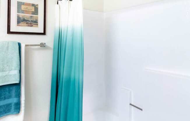 A white bathroom with a blue shower curtain.