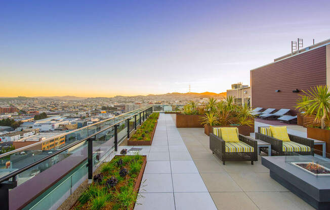 A rooftop patio with yellow chairs and plants.