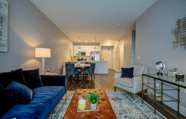 a living room with a blue couch and a coffee table in front of a kitchen at Barrington 101, Chicago