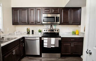 A kitchen with dark brown cabinets and a black stove top oven.