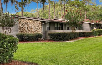 A house with a stone wall and a green lawn.