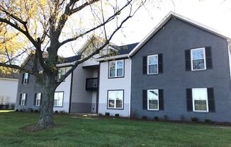 a gray house with a large tree in front of it