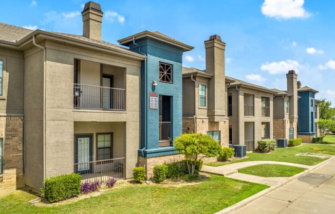 a row of townhomes with balconies and grass and a sidewalk