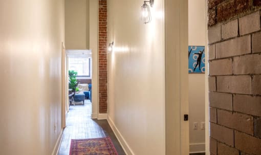 the hallway of a home with a brick wall and a carpet