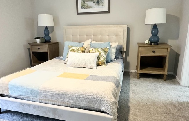 a bedroom with gray walls and a white bed with blue and yellow pillows