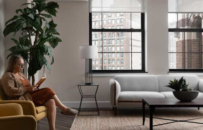 a woman sitting on a couch in a living room reading a book