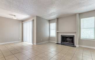 an empty living room with a fireplace and tiled floors