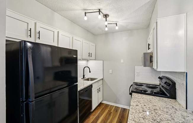 A black fridge and stove in a small kitchen.