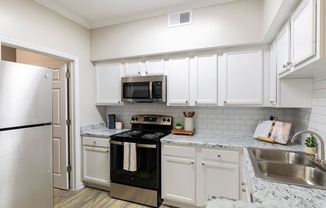 a kitchen with white cabinets and black appliances and a stainless steel refrigerator