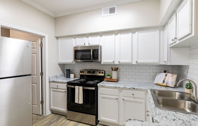 a kitchen with white cabinets and black appliances and a stainless steel refrigerator