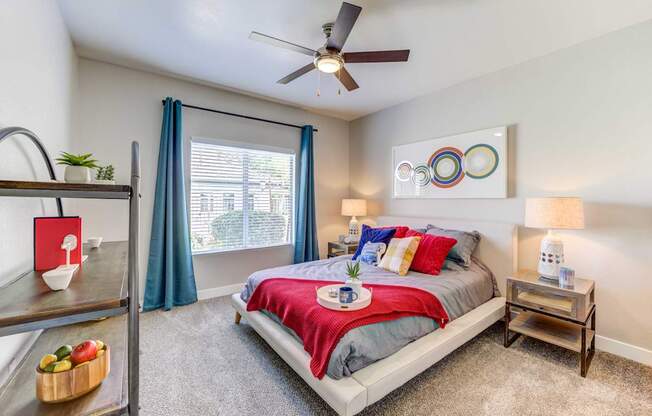 A bedroom with a bed, nightstand, and a fan.