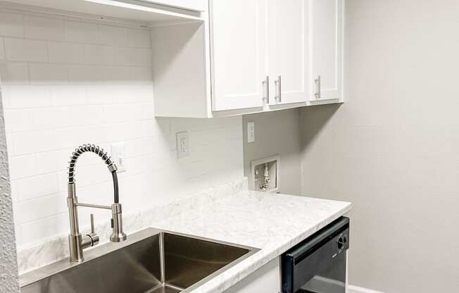 an empty kitchen with white cabinets and a sink