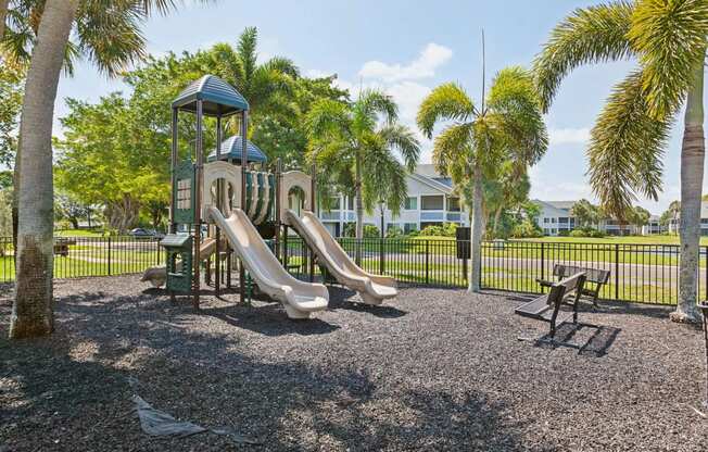 playground with slides and picnic tables in front of a house