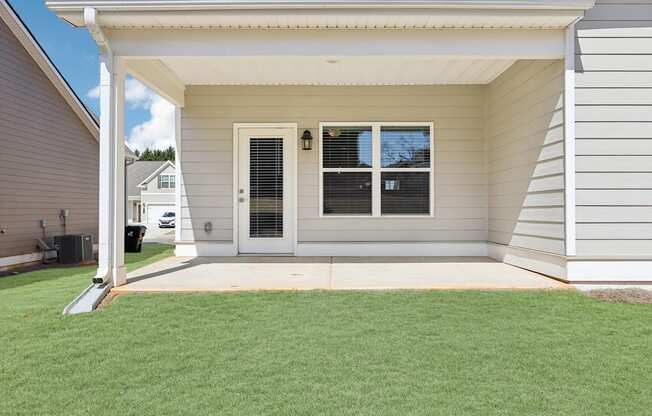 A house with a white door and windows with a green lawn in front.