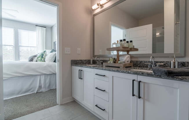 a bathroom with a sink and a mirror and a bedroom with a bed