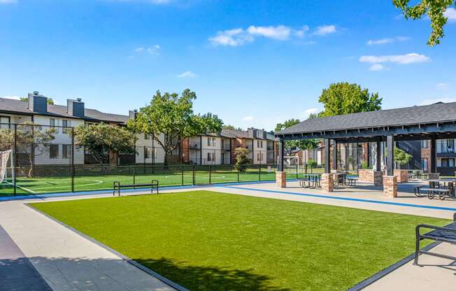 A sunny day at the park with a blue sky and a green lawn.