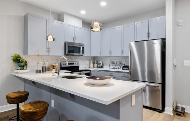 A modern kitchen with a white countertop and a stainless steel refrigerator.