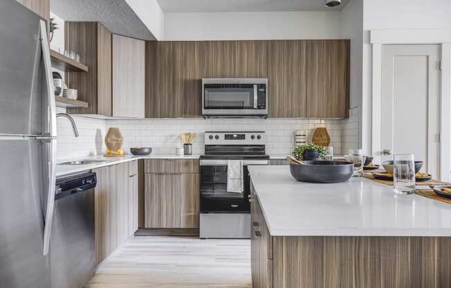 Kitchen with wood cabinetry, island countertop,  and stainless steel appliances