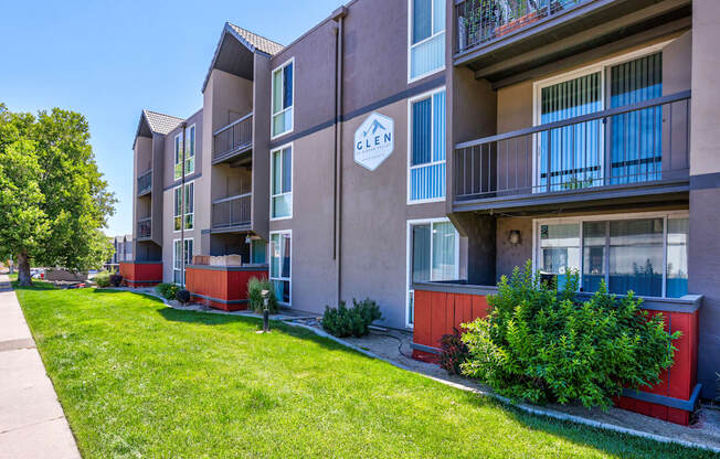 Apartment complex with balconies and greenery in front.