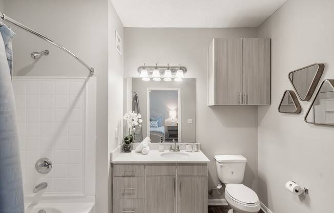 a bathroom with a shower toilet and sink and a mirror at Lagniappe of Biloxi Apartment Homes, Mississippi   , 39532