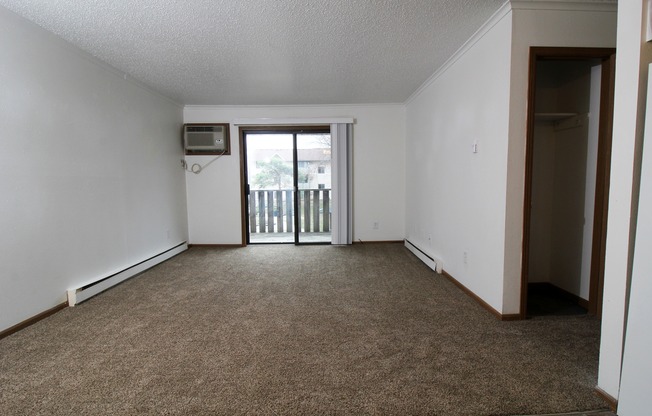 an empty living room with a door leading to a balcony