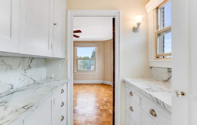 Kitchen with White Cabinets, Window, and Marble-look countertops and view into Living Area at Malloy Apartment Homes, Seattle, WA, 98105