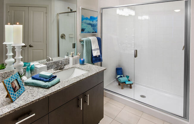 A bathroom with a sink, mirror, and a glass shower door.