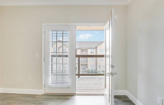 an empty living room with a door open to a balcony