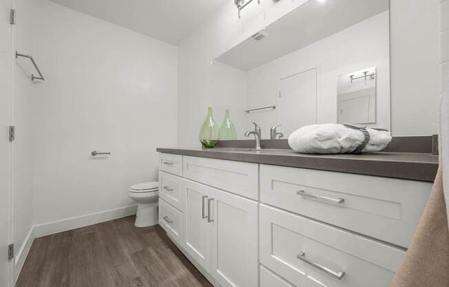 A bathroom with white cabinets and a white toilet.