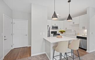 a kitchen with white cabinets and a white island with two stools