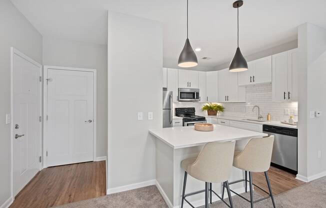 a kitchen with white cabinets and a white island with two stools