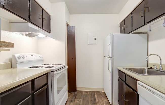 A kitchen with white appliances and brown cabinets.
