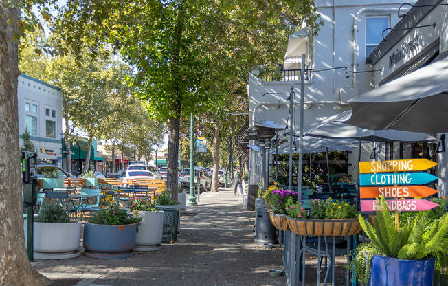 a city street with plants and umbrellas on a sidewalk