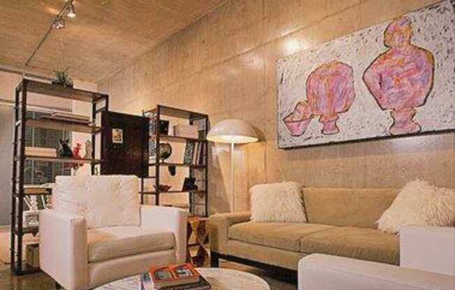 A living room with a white couch, a white chair, and a coffee table with a book on it.