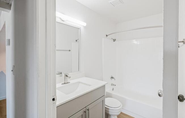 A white bathroom with a toilet, sink, and bathtub.