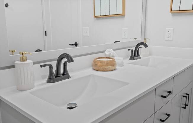 a white bathroom with two sinks and a mirror