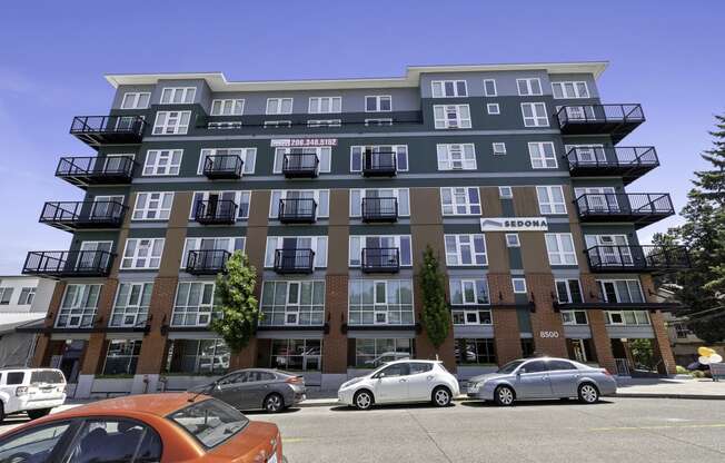 an image of the large property building with cars parked in front of it  at Sedona Apartments, Seattle, WA