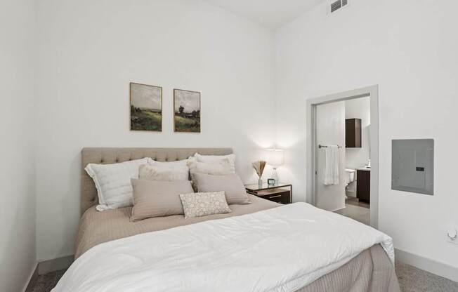 A bedroom with a large bed and two pictures on the wall.