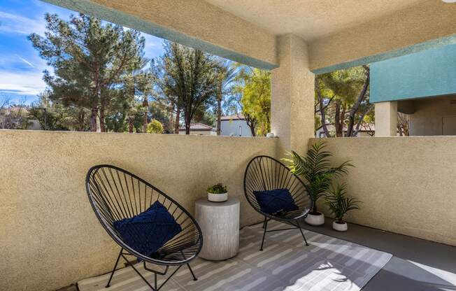 a patio with two chairs and a plant on a balcony at Mirasol Apartments, Las Vegas, NV